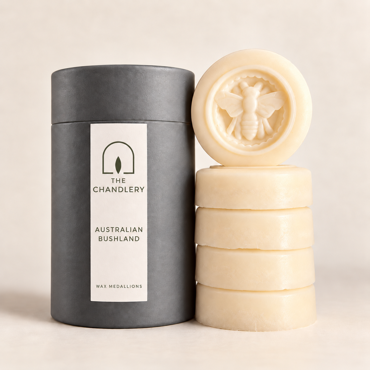 The Chandlery Australian Bushland wax medallions stacked beside their labelled charcoal tube, with a raised bee design on the top medallion.