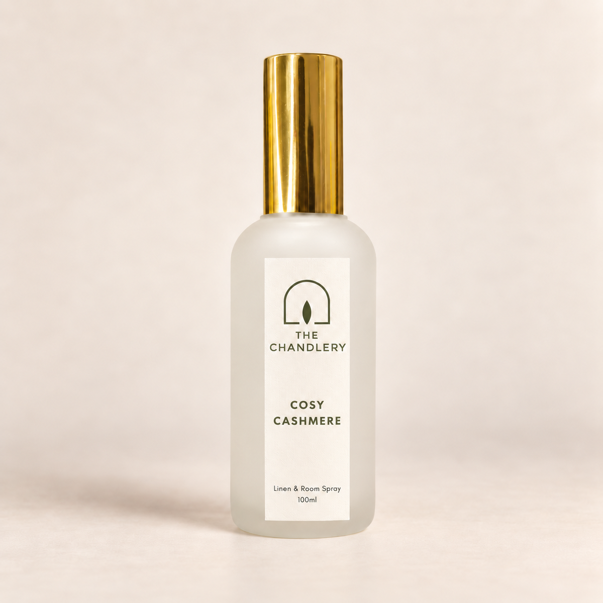 The Chandlery Cosy Cashmere room spray in a frosted glass bottle with a gold spray top, photographed against a soft neutral backdrop.