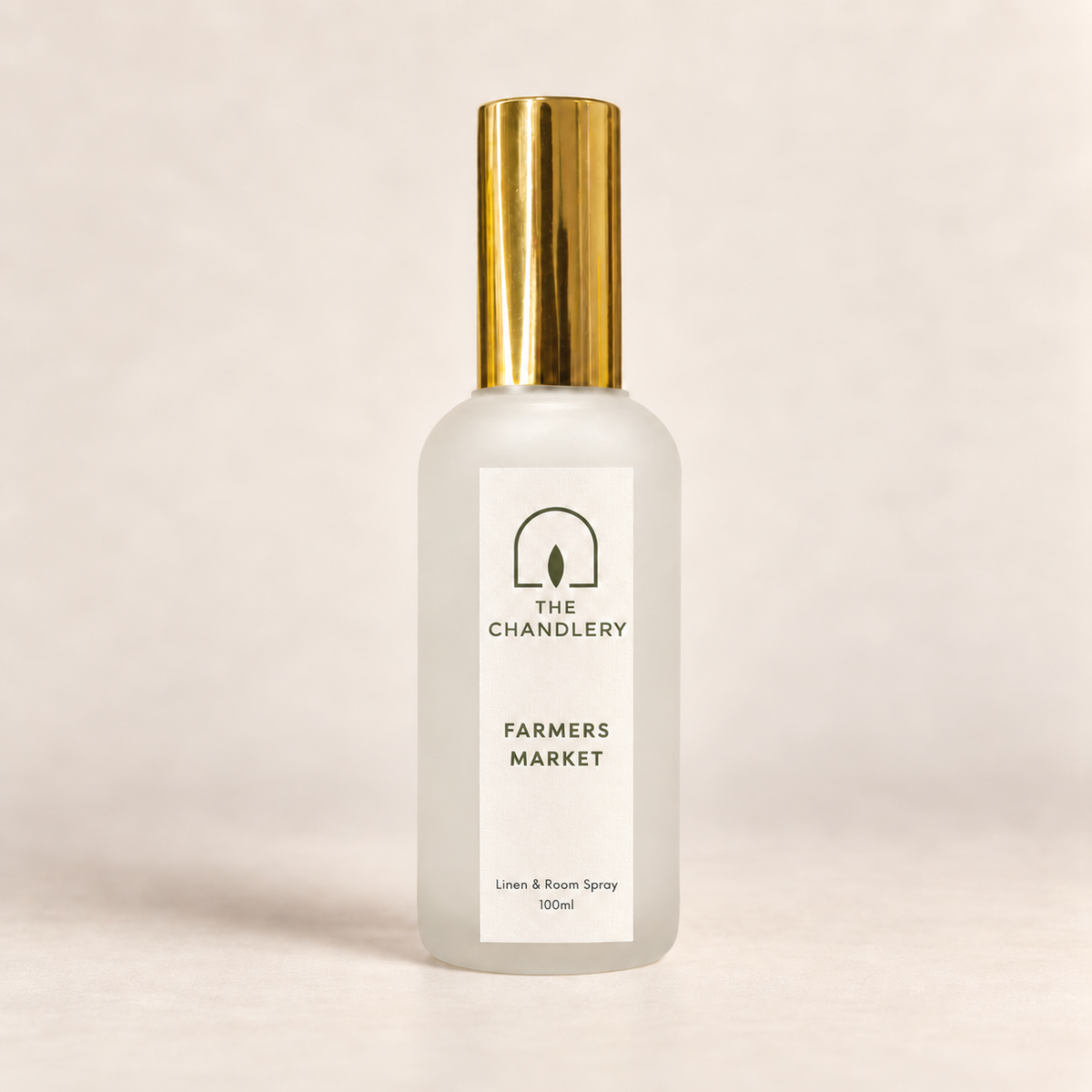 The Chandlery Farmers Market room spray in a frosted glass bottle with a gold spray top, photographed against a soft neutral backdrop.