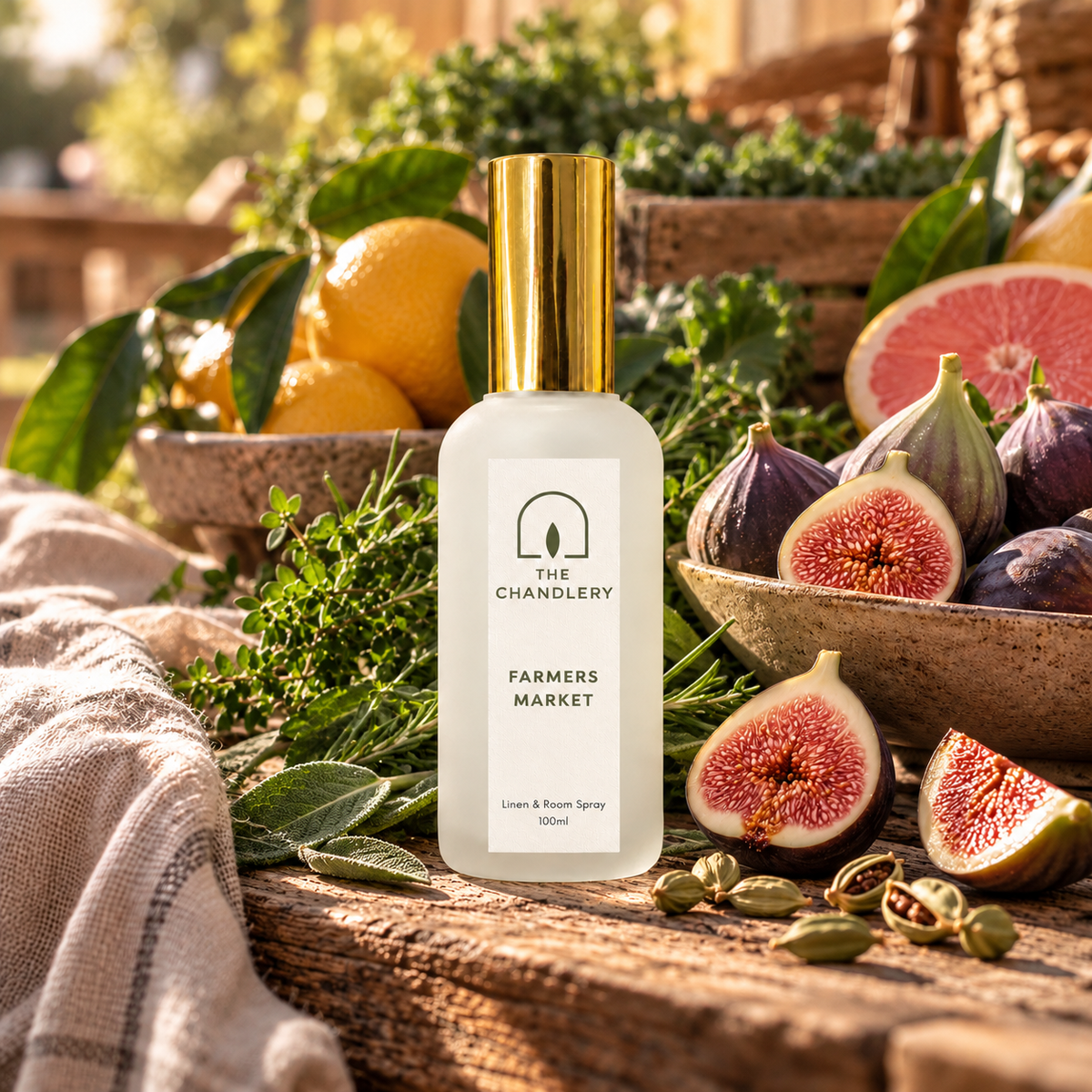 Farmers Market room spray surrounded by fresh figs, citrus and leafy herbs on a rustic market table.