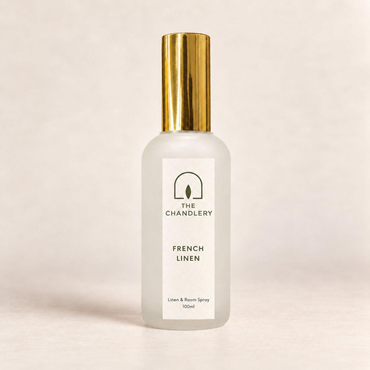 The Chandlery French Linen room spray in a frosted glass bottle with a gold spray top, photographed against a soft neutral backdrop.