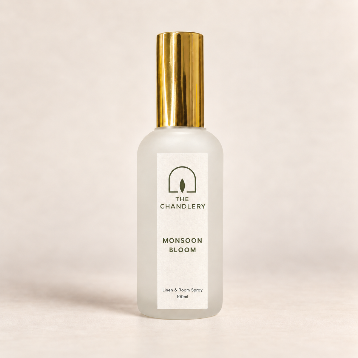 The Chandlery Monsoon Bloom room spray in a frosted glass bottle with a gold spray top, photographed against a soft neutral backdrop.