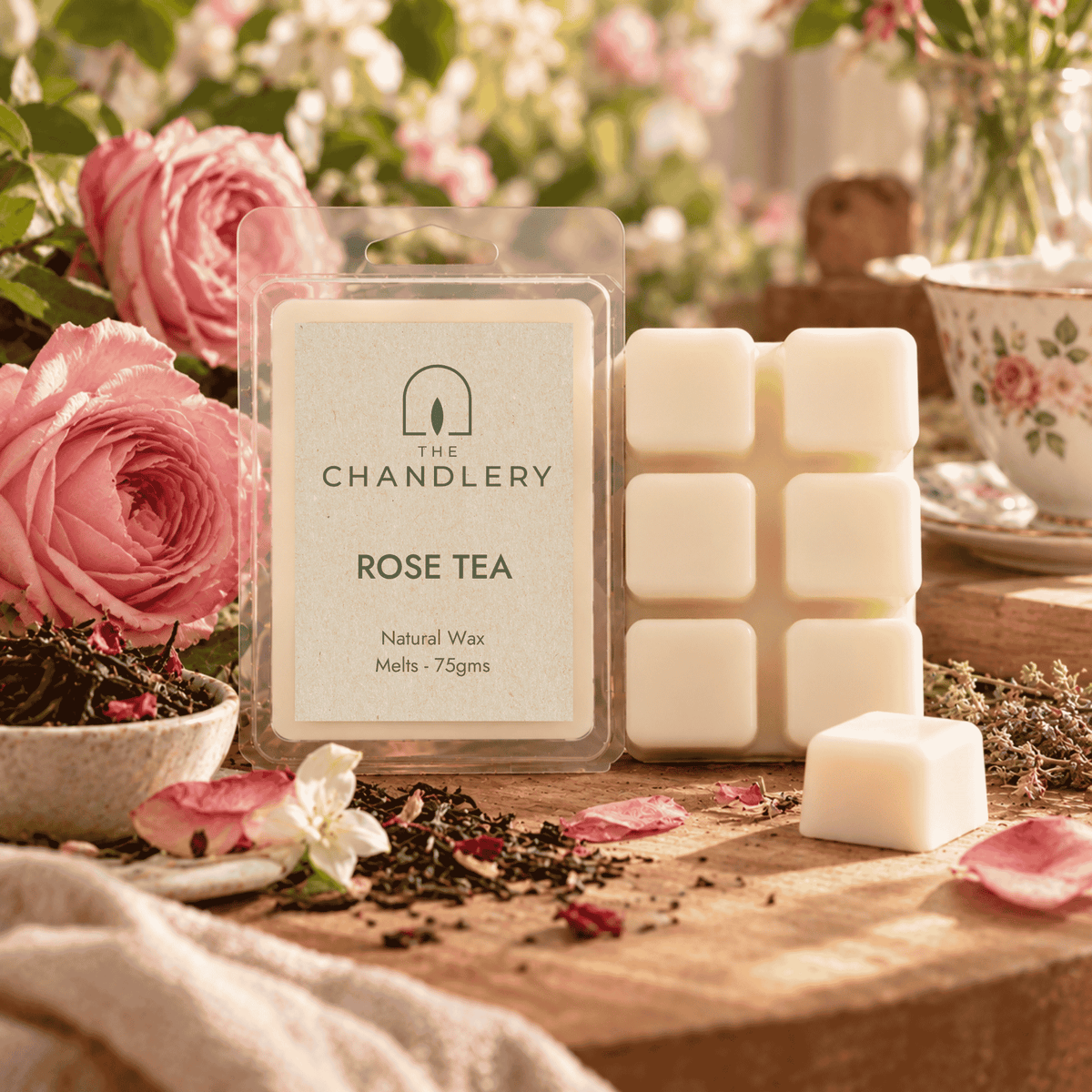 Rose Tea wax melt packet and ivory six-cube bar with a loose cube, pink roses, loose tea and floral teaware.