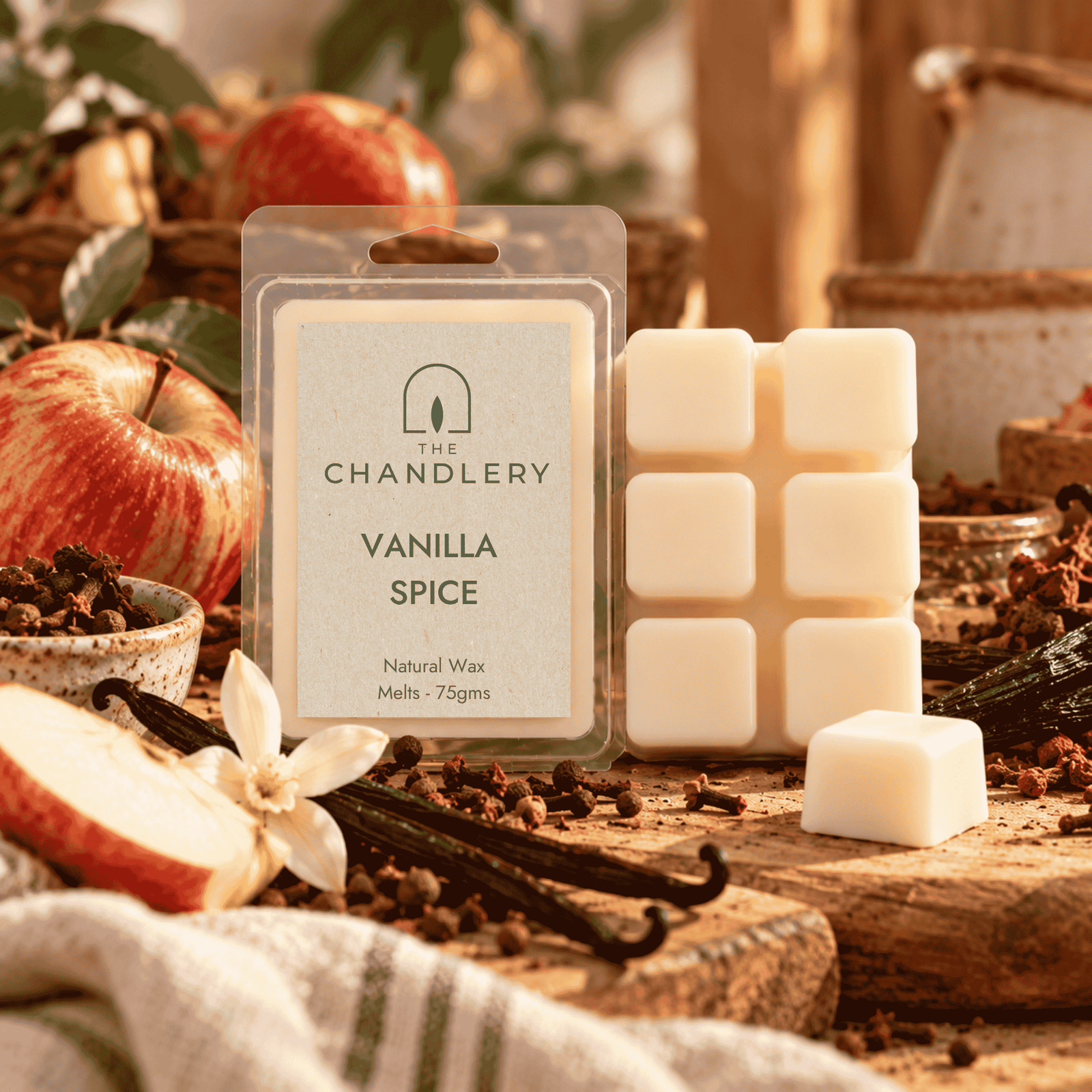 Vanilla Spice wax melt packet and ivory six-cube bar with a loose cube, apples, cloves and vanilla pods.